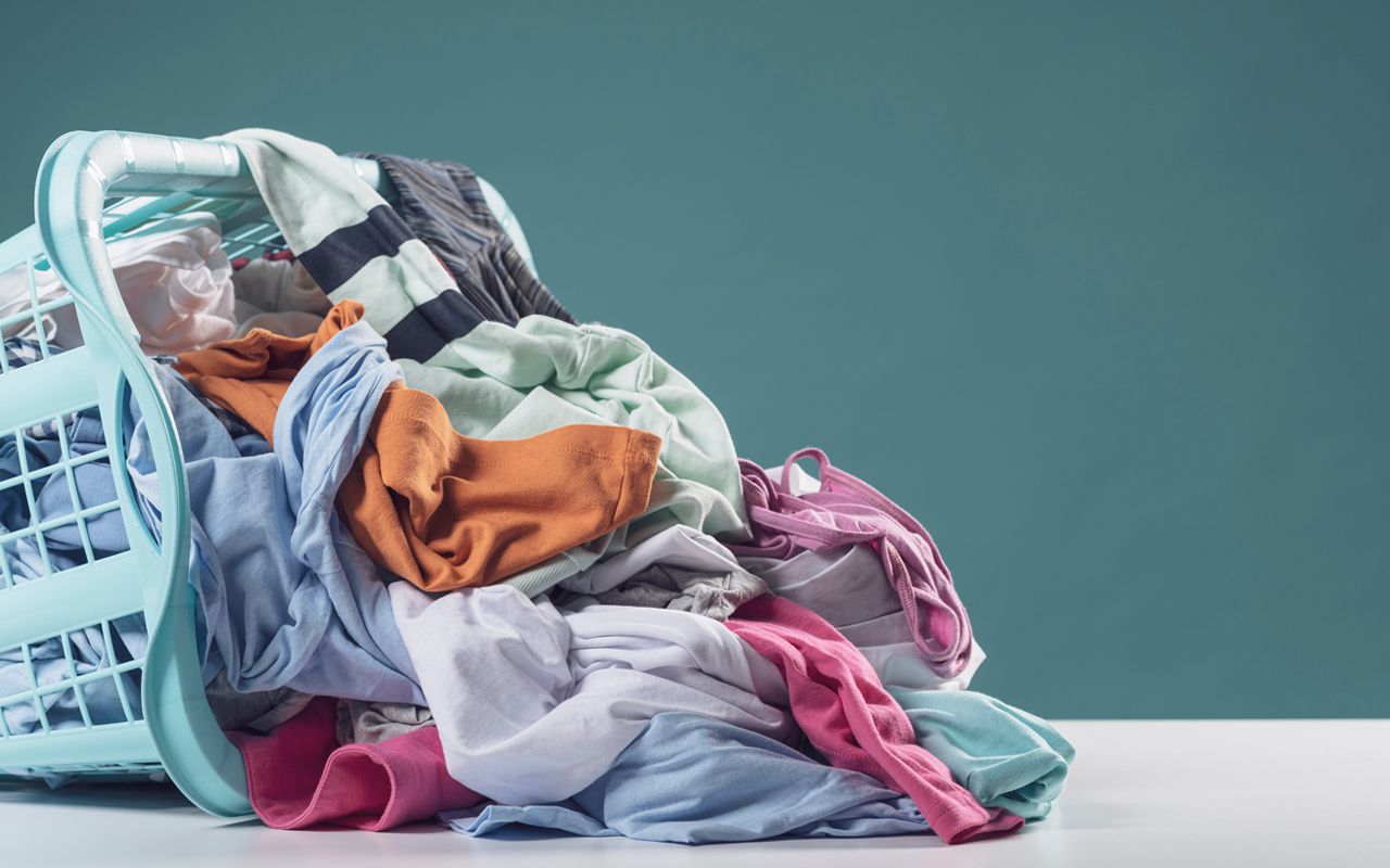 Washing basket on it's side with a pile of clothes falling out of it.