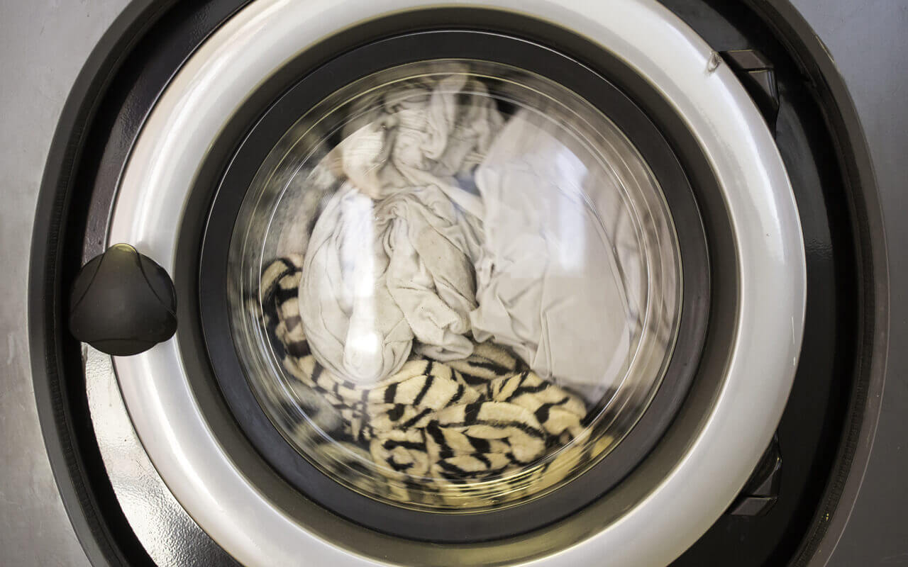 A closed washing machine filled with clothes.